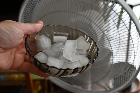 Ice cubes held in front of a fan for home cooling Stock Photos