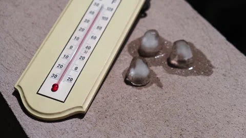 Ice cubes melting in direct sun next to a home thermometer Видео 247216670