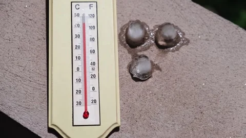 Ice cubes melting in direct sun next to a home thermometer Видео 247216676
