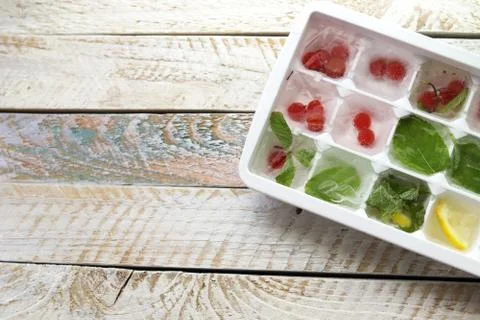 Ice cubes with mint, lemon and red berries in a tray for making drinks Stock Photos