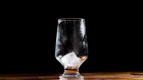 Ice Cubes Placed into Chilled Glass Against Black Studio Background Stock Footage 337862515