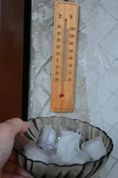 Ice Cubes on Plate with Thermometer Close-Up, Heatwave at Home Cooling Concept Stock-Fotos