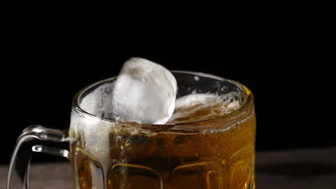 Ice cubes poured into cold beer In a mug on a black background Stock Footage 145275532