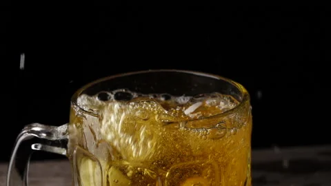 Ice cubes poured into cold beer In a mug on a black background Stock Footage 145275672