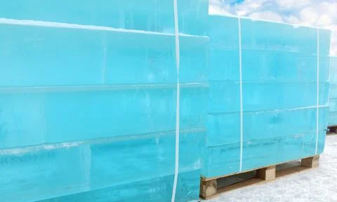 Ice is cut into the shape of bricks and stacked on pallets. Stock Photos