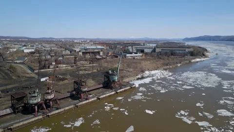 Ice Drift Occurs on a River next to the Port with Big Cranes and Factory Stock Footage 194344138