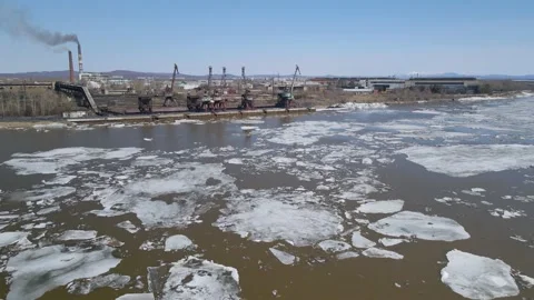 Ice Drift Occurs on a River next to the Port with Big Cranes and Factory Stock Footage 194344414