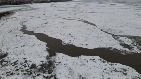 Ice Drift Occurs on the River next to a Island with Forest, Aerial view above Stock Footage 194345189