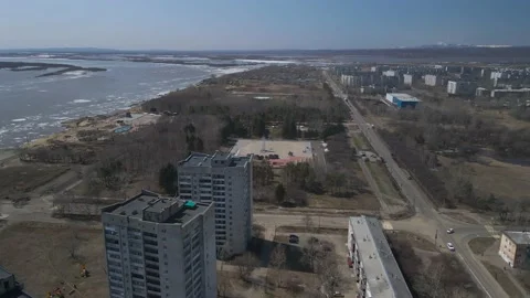 Ice Drift Occurs on the River next to High Buildings in City, Mountain Stock-Footage 194345630