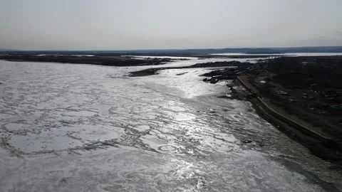 Ice Drift Occurs on River next to a Mountains Ridges and Village on a Island Stock Footage 194347681