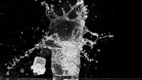 Ice dropped into glass in super slow motion. Shot with cinema camera RED DRAGON Video stock 123711935
