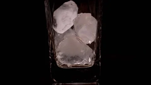 Ice falling into an empty glass on black background, slow motion. Empty glass Stock Footage 150779195