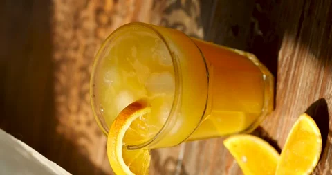 Ice falls into orange juice. Close-up vertical Stock Footage 246001607