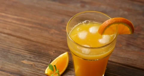 Ice falls into orange juice. Close-up Stock Footage 246001728