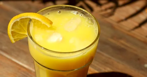 Ice falls into orange juice. Overhead view Stock Footage 246063253