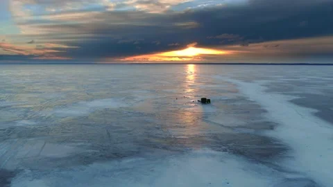 Ice fishing camp, isolated on a vast plane of ice at sunrise Stock Footage