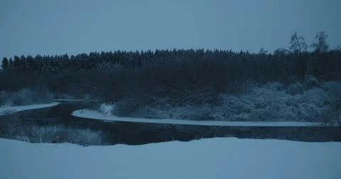 Ice Floes Drifting on Spring River Against Snowy Forest at Dusk Stock Photos