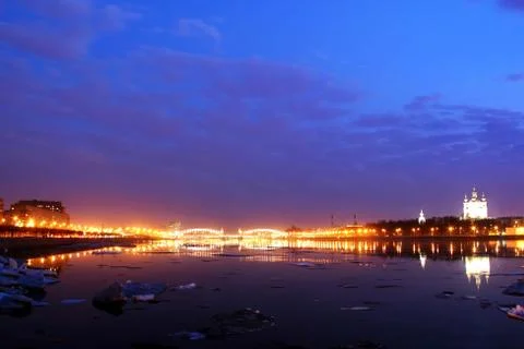 Ice floes float on the night river embankment of the city with illumination Stock Photos