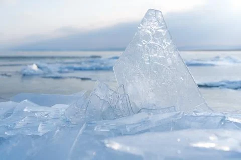 Ice formations on a calm lake surface under a cloudy sky during winter day Foto stock