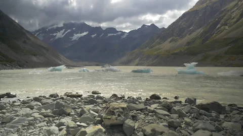 Ice formations float on a lake surrounded by mountains, in New Zealand Stock Footage 215336583