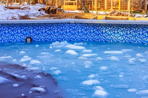 Ice forms on surface of pool during winter in rural backyard setting Stock Photos