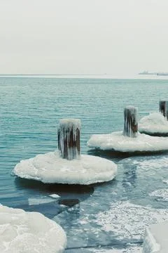 Ice forms on wooden posts at the edge of a lake on a cold winter day with a.. Stock Photos