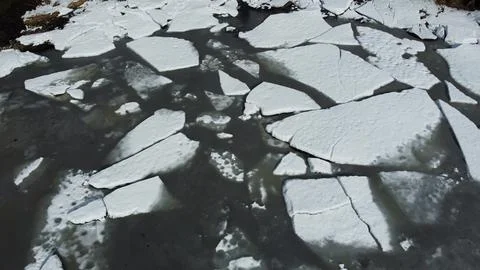 Ice fragments float on water in a natural setting during daytime Stock Photos