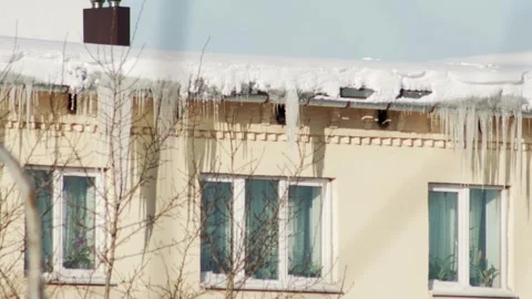 Ice icicles and snow hang from the roof of a house in winter. Danger of falling Video stock 253472931