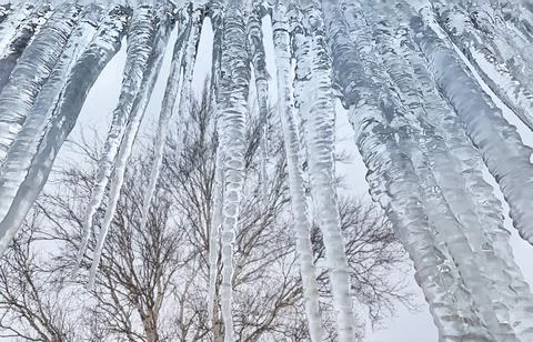 Ice icicles hanging down a solid wall. Stock Photos