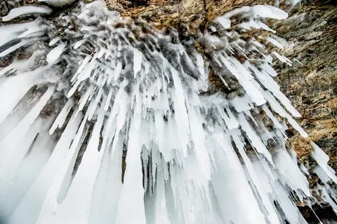 Ice icicles hanging on stone surface of cave, frozen water in winter Stock-Fotos