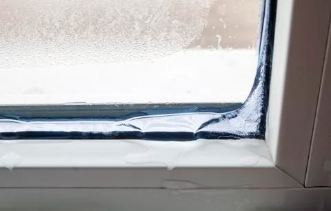 Ice inside in the corner of a window in winter. Poor warm isolat Stock Photos