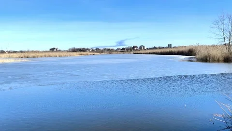 Ice melting on calm river under clear blue sky in early spring, Stock Footage 338241793