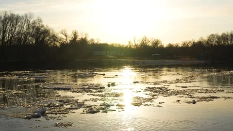 Ice melts river sunset current, nature's ice art, russet sunset hues, serene Stock Footage 274061242