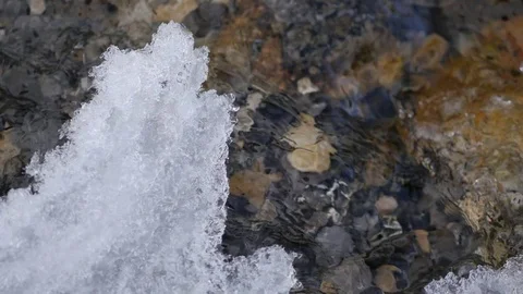 Ice Over the Clear Water Stream in Fresh Snowed Mountains 4K Stockbeeldmateriaal 80932134