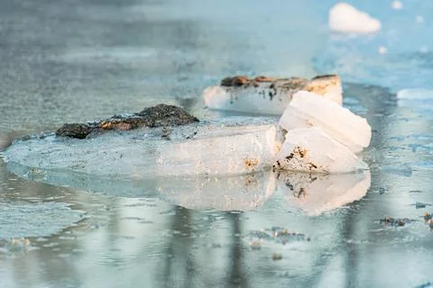 Ice patch floating on river, rough and irregular with dark specks Clear undis Stock Photos