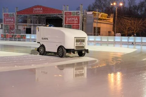 Ice resurfacing machine cleans skating rink during evening in a winter even.. Stock Photos