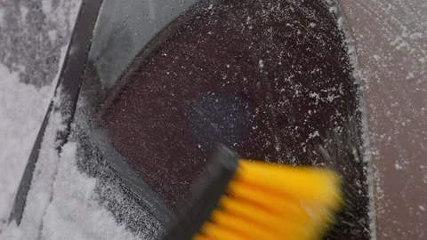 An ice scraper clears snow from a car window. Medium shot. 库存影片 312171477