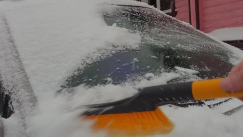An ice scraper clears wet snow from the car's surface. Medium shot. Stock Footage 312171496