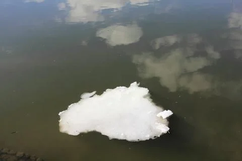 Ice in the shape of a cloud and reflection of clouds Stock Photos