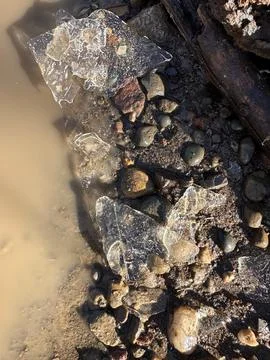Ice Shards Next to Muddy Puddle on Rocks Stock Photos