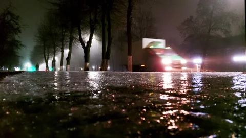 Ice on the sidewalk against the background of the road with car headlights at Stock Footage 300869537