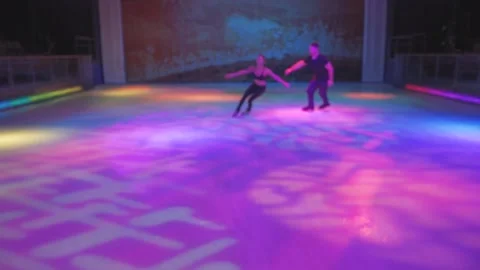 Ice skaters couple performance on empty purple blue light rink Stock Footage 137456050