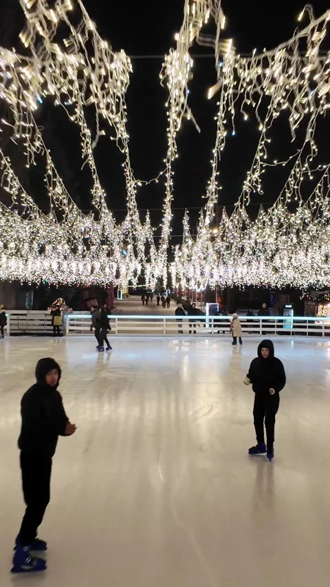 Ice skating under glowing festive lights on a winter night Stock-Footage 310609693