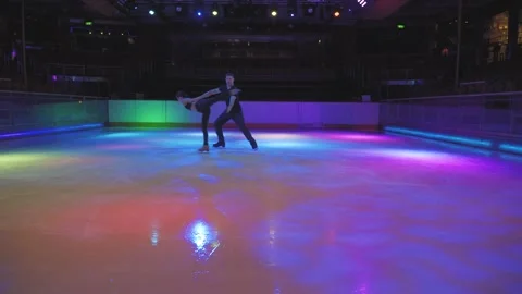 Ice skating upside down spin by skaters couple on empty purple blue arena Stock Footage 137456035