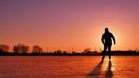 Ice speed skating silhouette in light of setting sun on frozen lake. Silhouette  Stock Footage 84706221