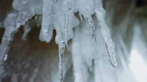 Ice tapering stalactites hang on ceiling of cave. Icicles melting inside grotto Vidéo 166566789
