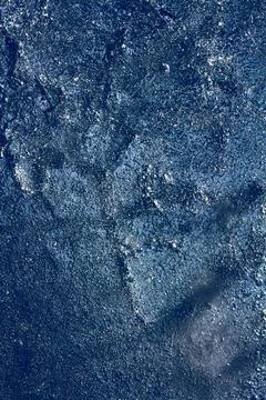 Ice texture with frozen bubbles and cracks on a dark blue background Stock Photos