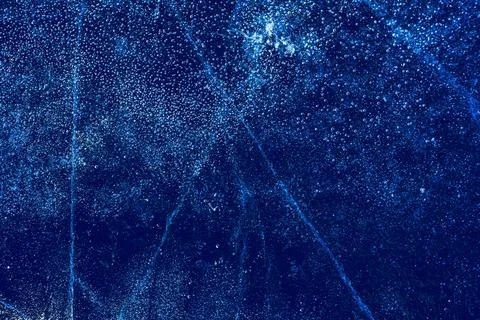 Ice texture with frozen bubbles and cracks on a dark blue background Stock Photos