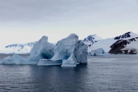 Iceberg in antarctic ocean with mountain, stormy sky, Antarctica Stock Photos