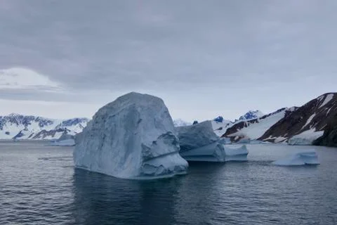 Iceberg in antarctic ocean with mountain, stormy sky, Antarctica Stock Photos